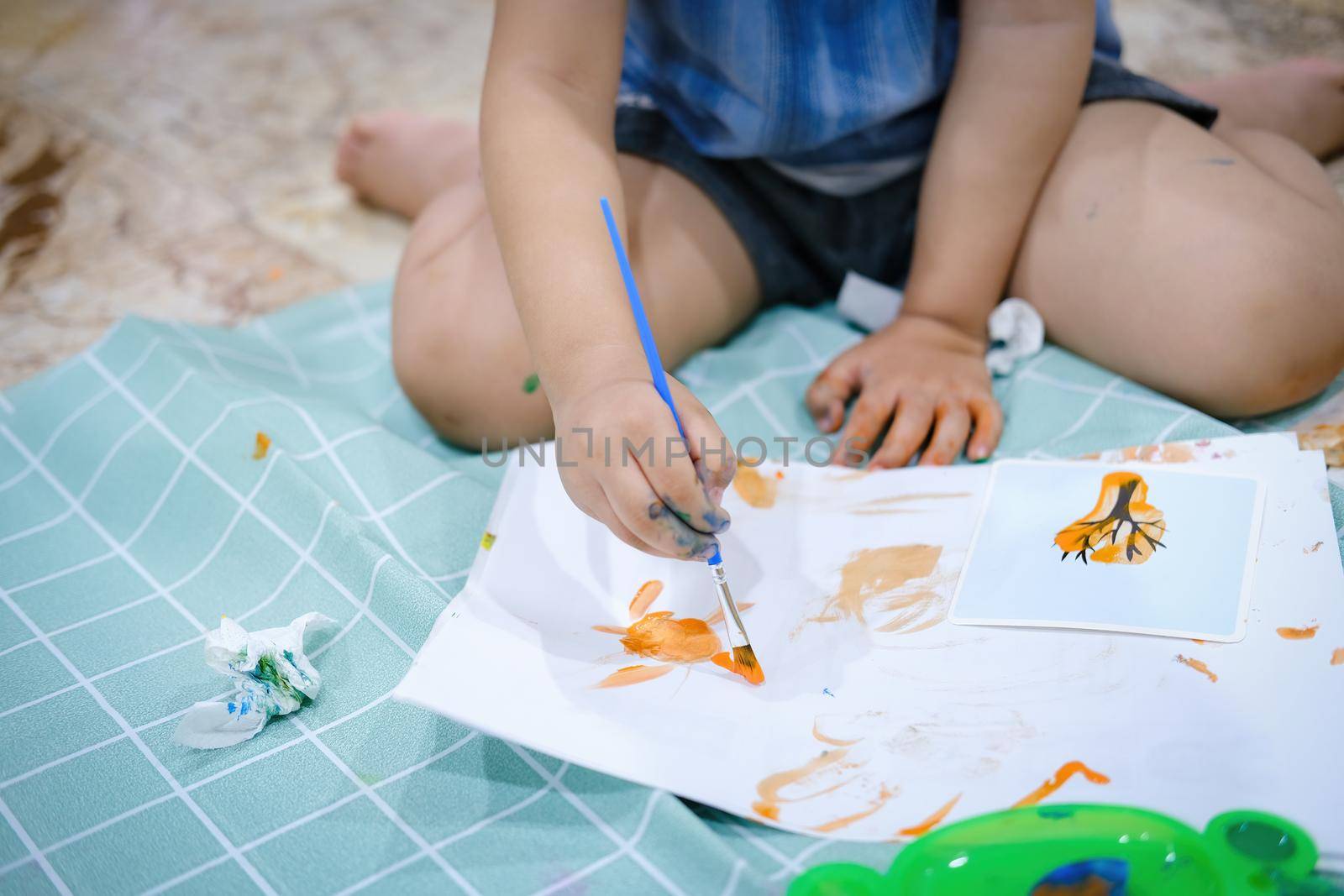 Focus on hands on paper. Children use paintbrushes to paint watercolors on paper to create their imagination and enhance their learning skills. by Manastrong