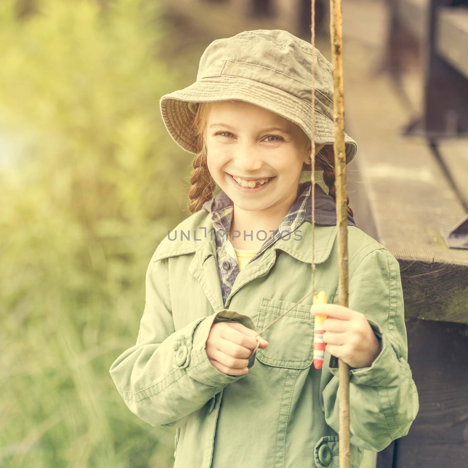 little fisher girl smiles holding a rod