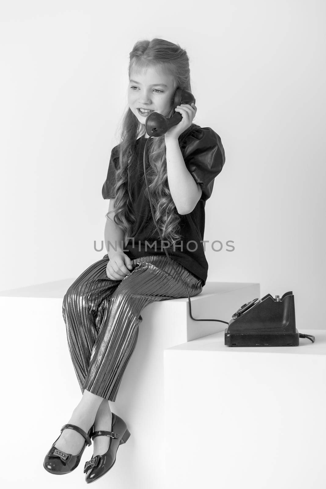 A little girl is ringing on the old phone. by kolesnikov_studio