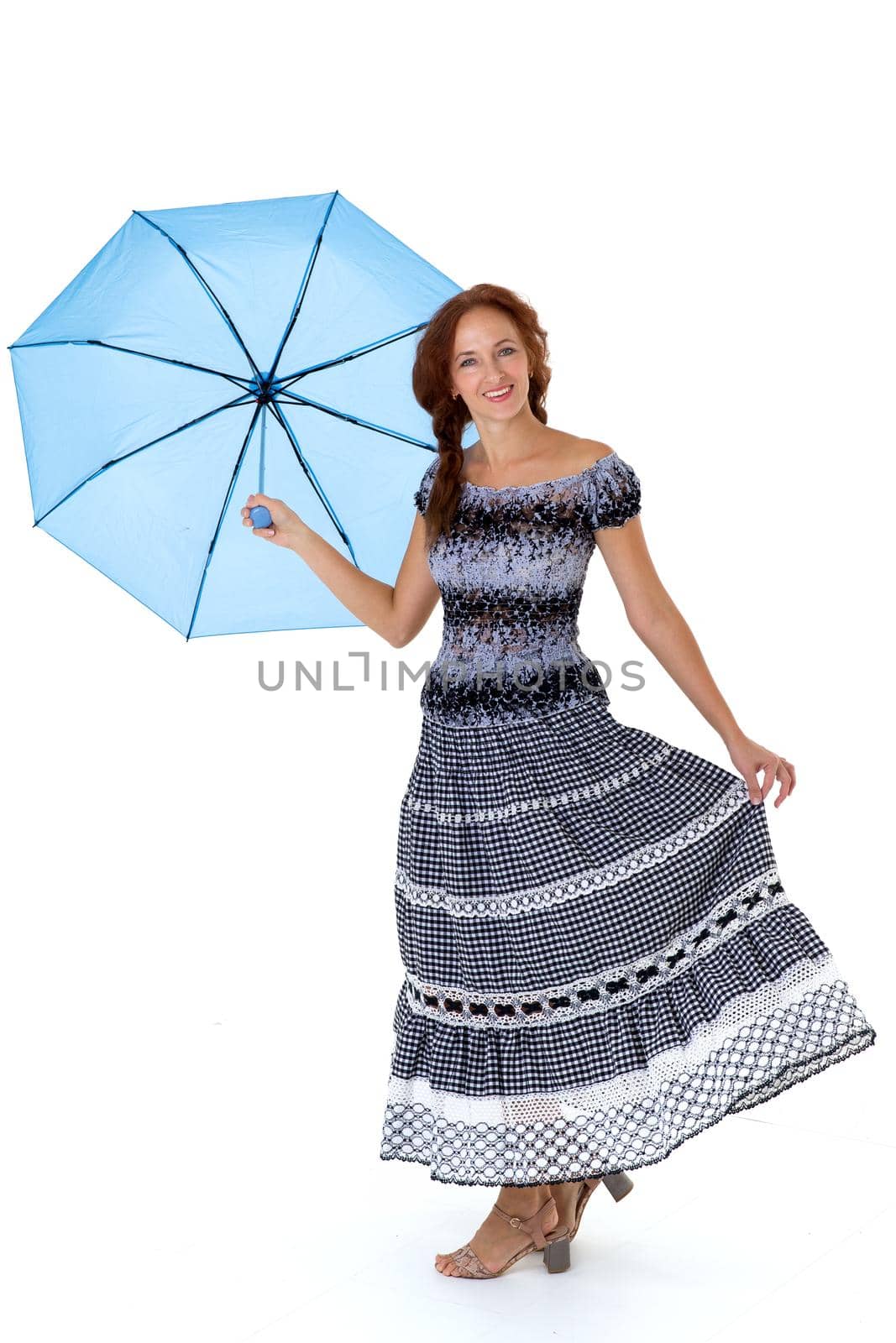 Happy girl holding umbrella above her head at arm length. Beautiful woman wearing summer dress walking under umbrella. Full length portrait of joyful woman smiling at camera against white background.