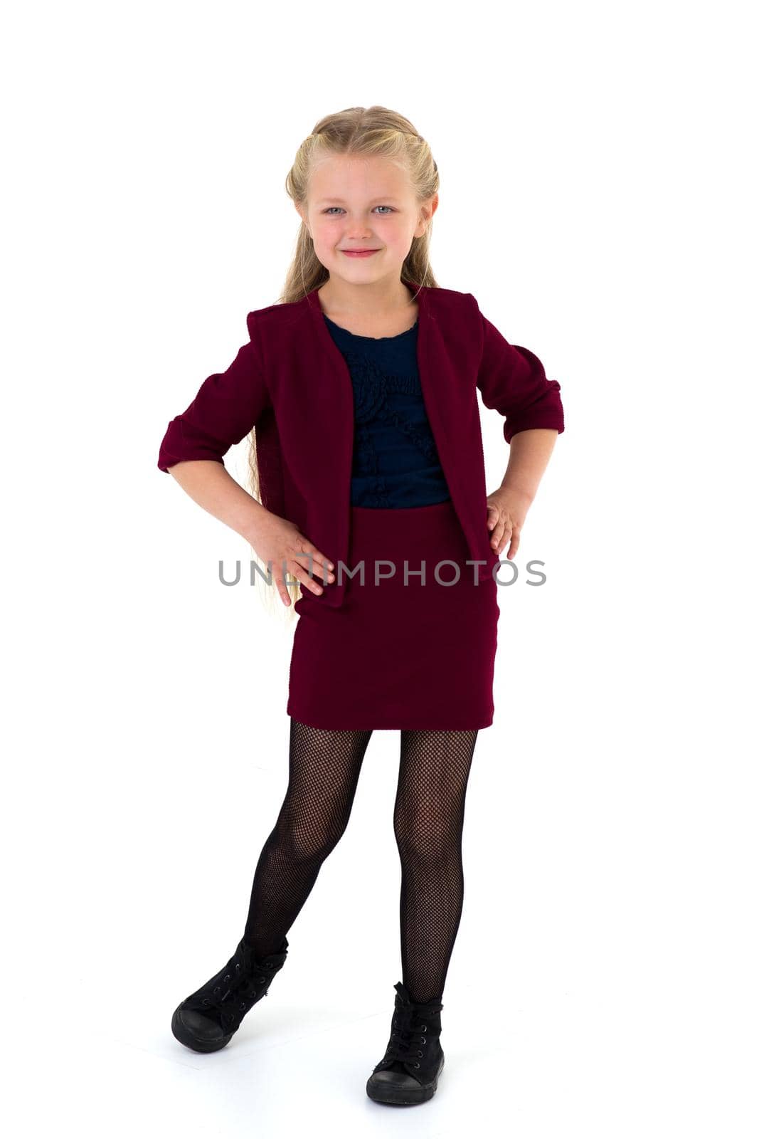 Cute happy blonde girl. Adorable stylish long haired kid in fashionable clothes standing on isolated white background. Lovely little girl posing in studio smiling at camera