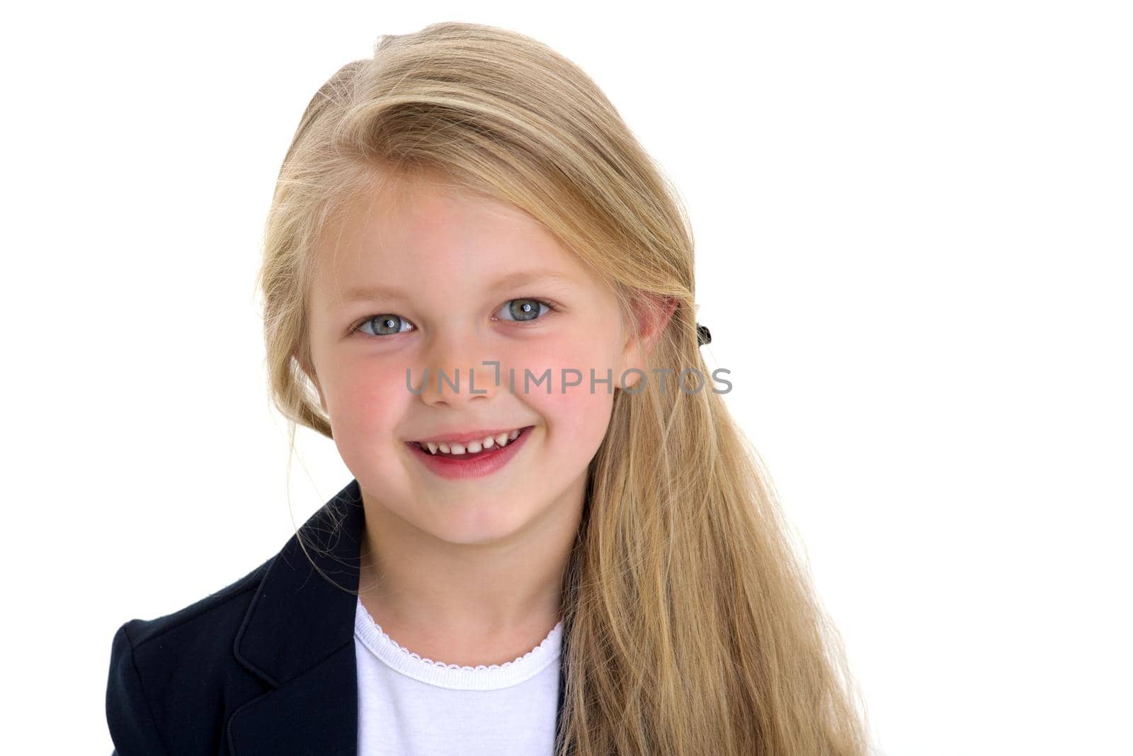 Portrait of adorable blonde little girl. Curious beautiful long haired schoolgirl standing against white background. Lovely elementary school student in blue jacket and white blouse