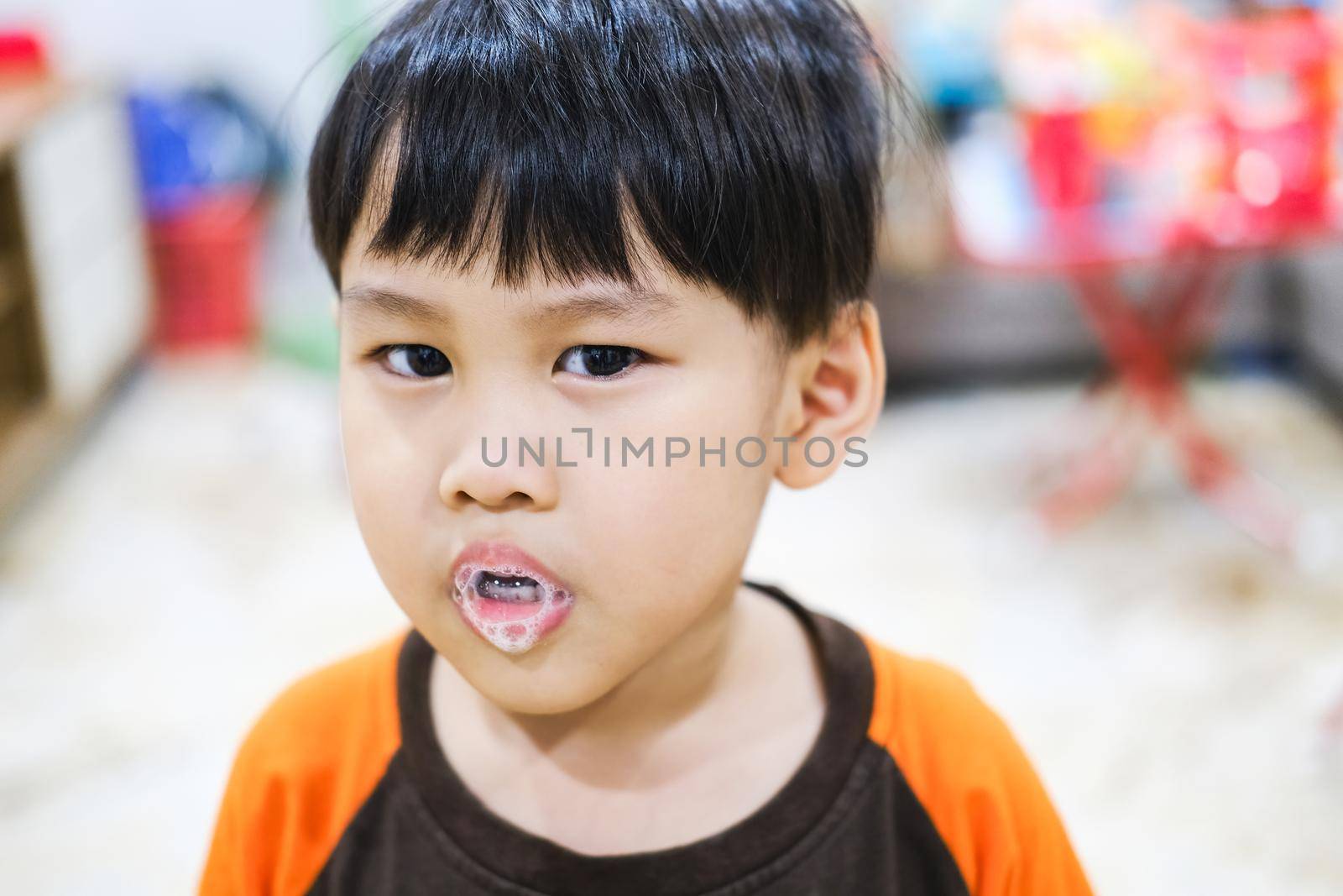 A young child is enjoying the froth of saliva spitting out of his mouth