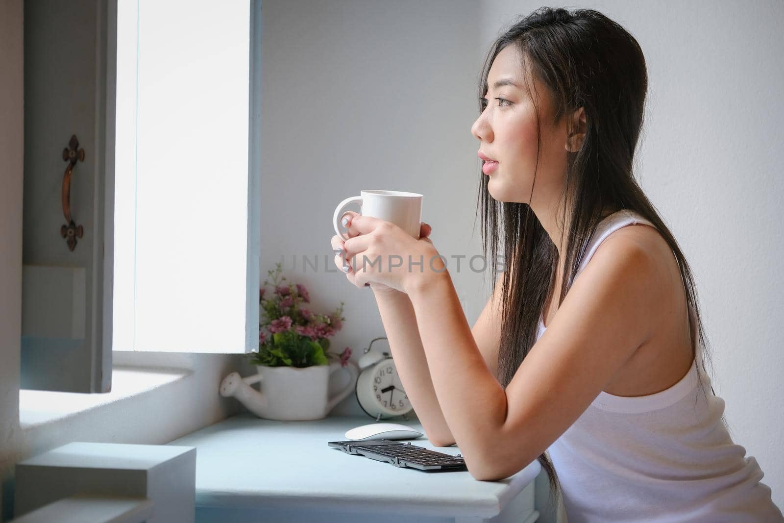 Smiling calm young woman drinking coffee at home