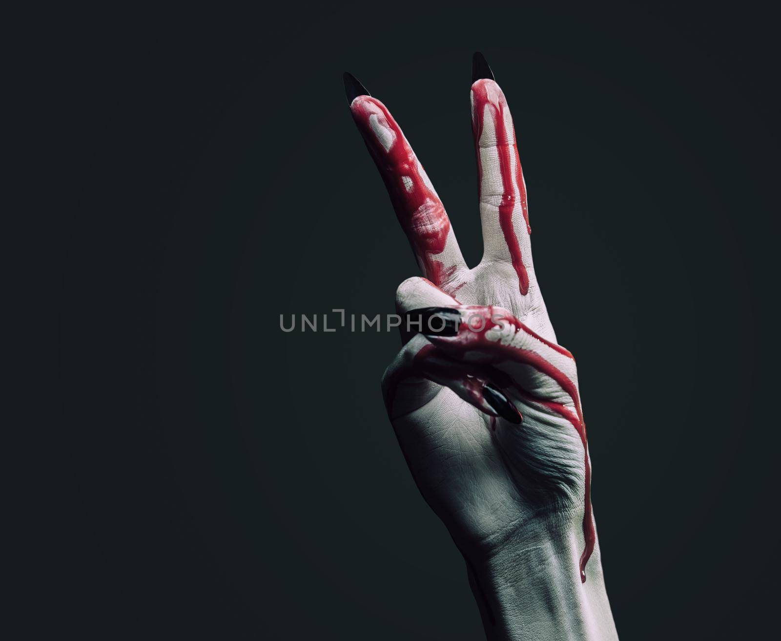 Vampire hand in blood on dark background, peace hand sign. Halloween or horror theme