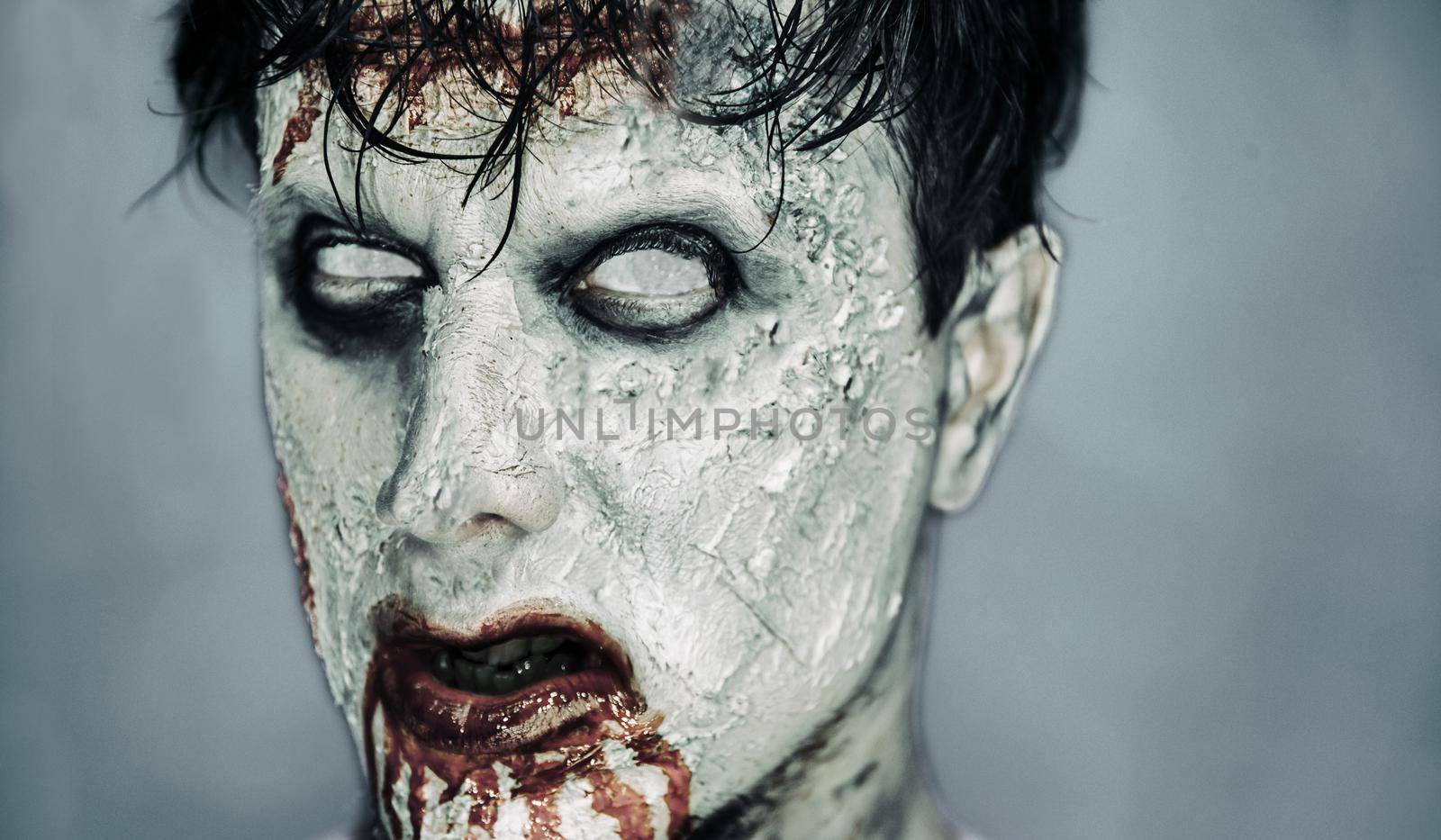 Portrait of scary bloody zombie man with white eyes. Halloween or horror theme