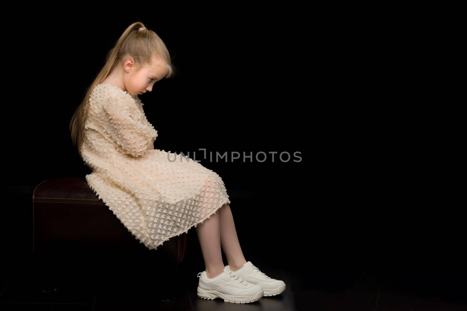 Beautiful studio portrait of a little girl in profile. On a black background.