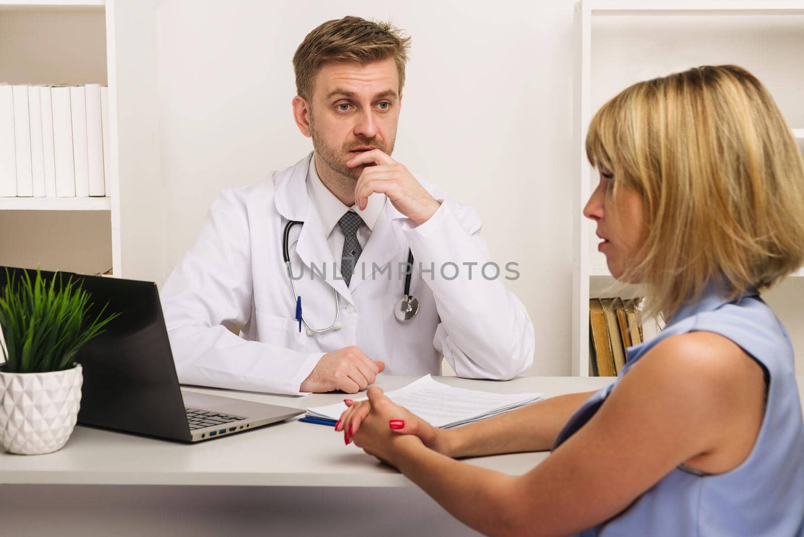 Young woman on a consultation with a male surgeon or therapist in his office. by zartarn