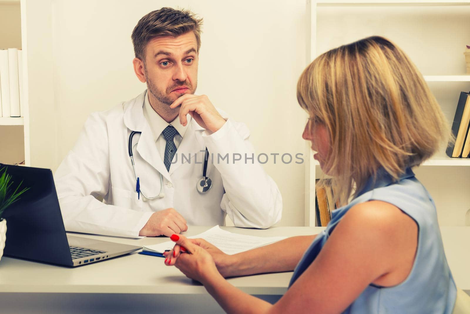 Young woman on a consultation with a male surgeon or therapist in his office. Selective focus on the doctor.toned