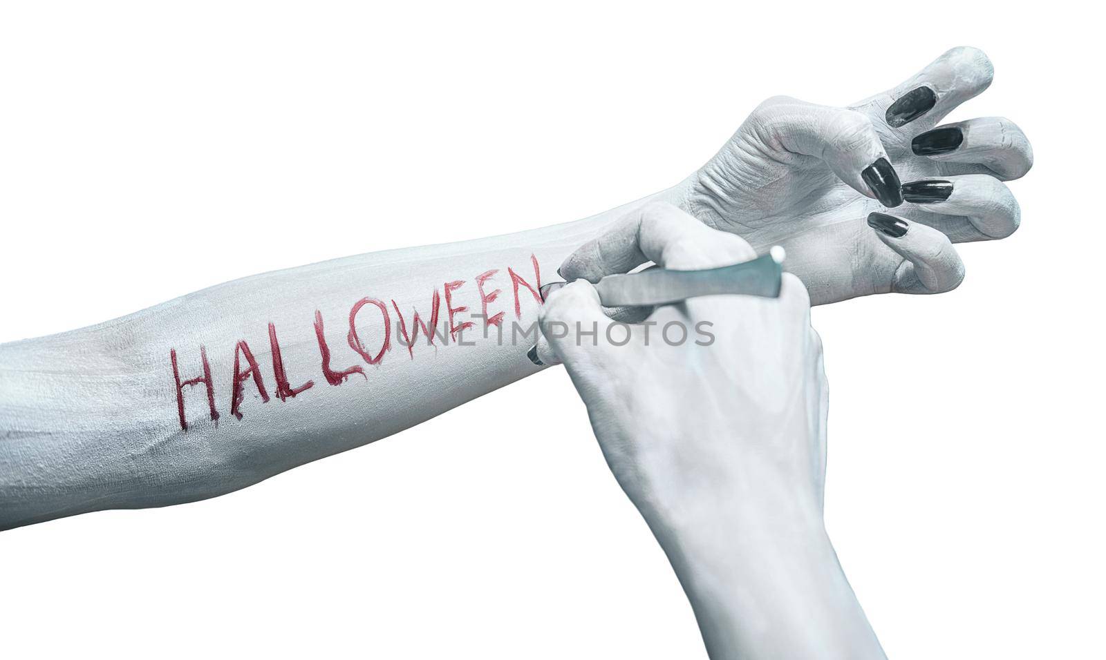 Unrecognizable dead woman writes the word halloween by scalpel on her arm, view of human arms