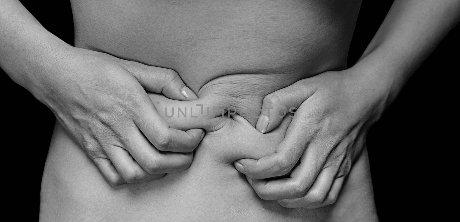 Unrecognizable woman holds her abdomen, menstrual pain, monochrome image