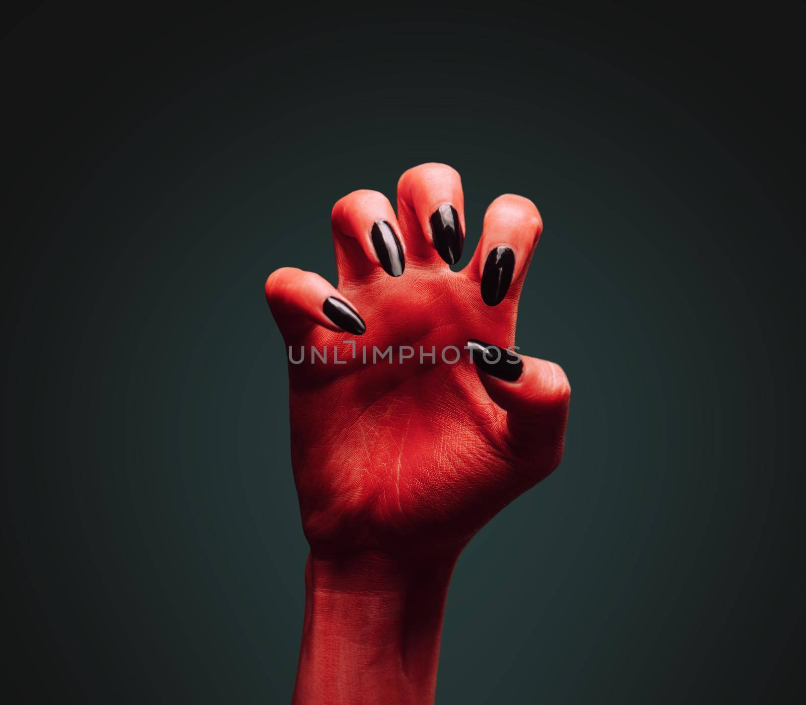 Scary red devil hand on dark background. Halloween or horror theme