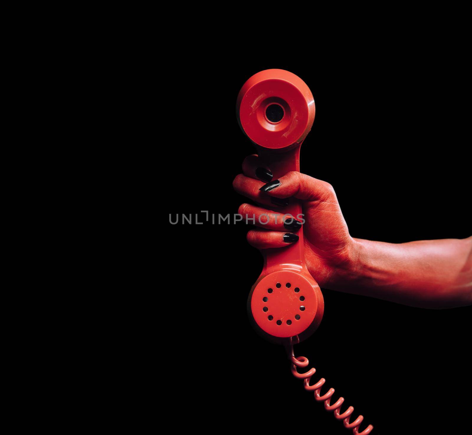 Red devil hand gives phone handset on dark background, space for text, Halloween or horror theme