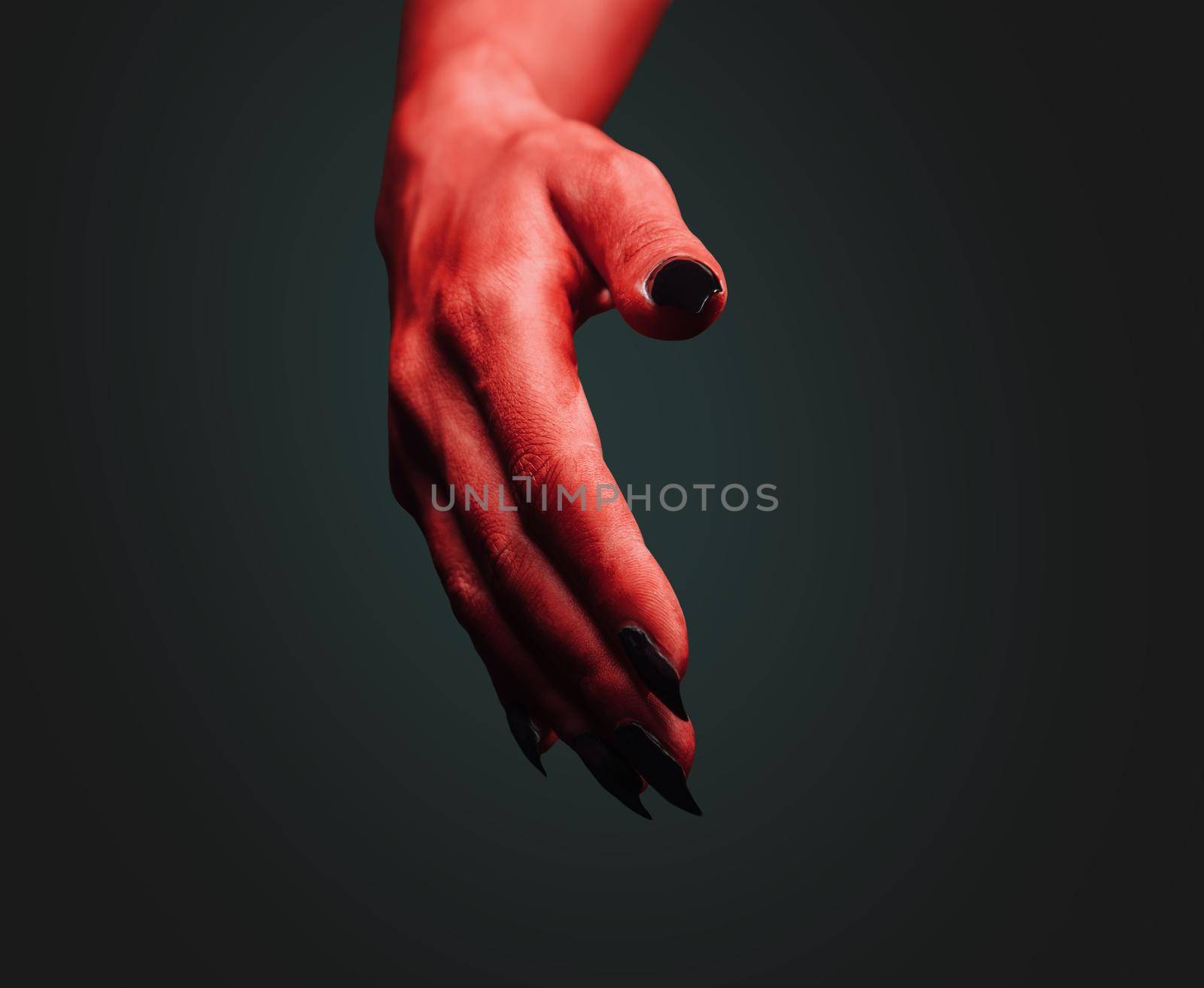Red demon hand with handshake gesture on dark background. Halloween or horror theme