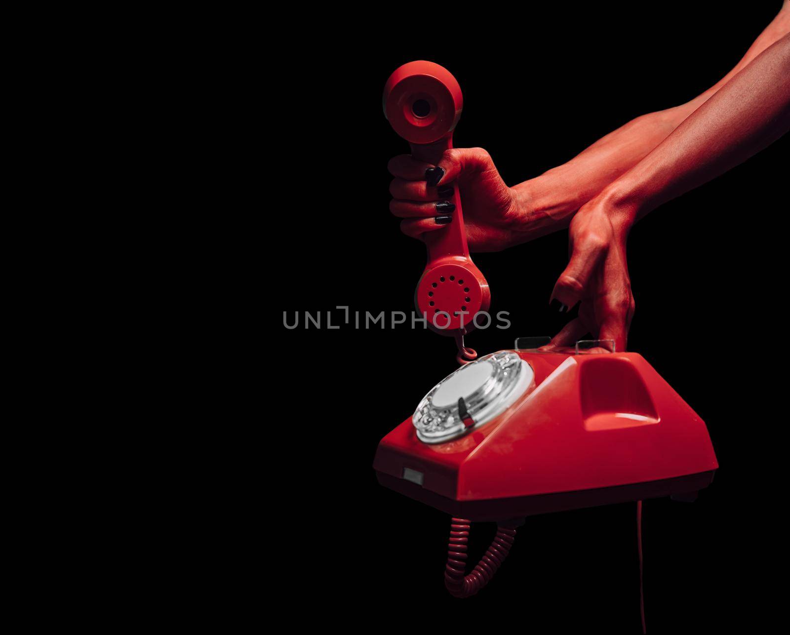 Red devil hands giving retro phone on dark background, space for text, Halloween or horror theme