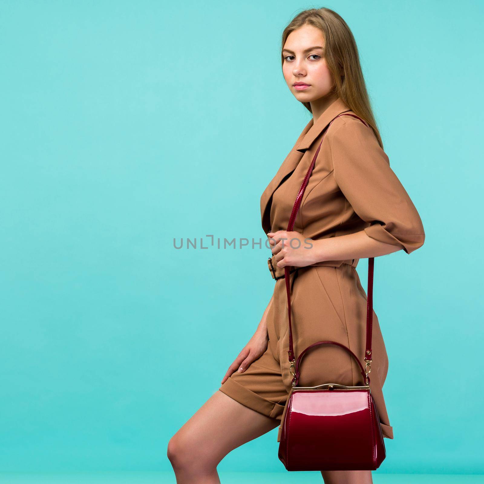 Young fashion woman hold handbag clutch isolated on blue background - image