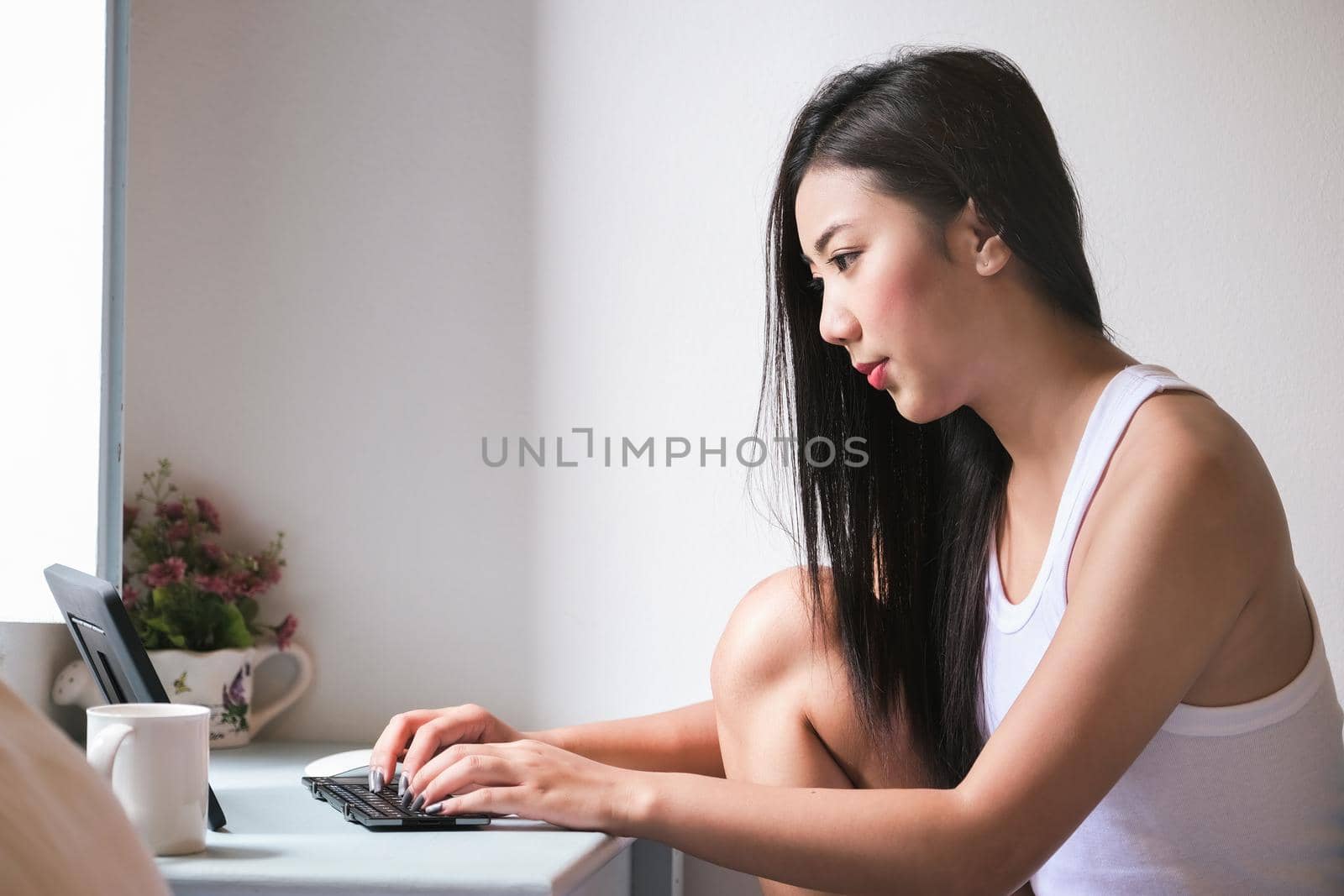 new normal, a businesswoman using computer to work for a company Via the internet on your desk at home. by Manastrong
