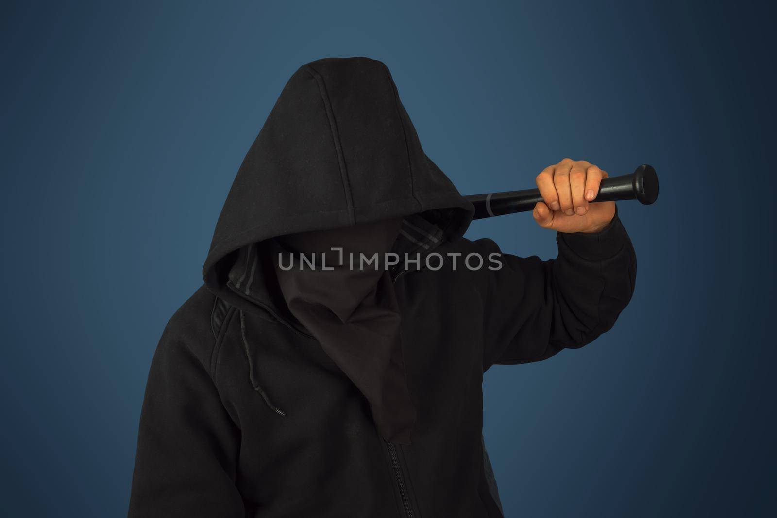 Hooligan man in hood and mask holds baseball bat