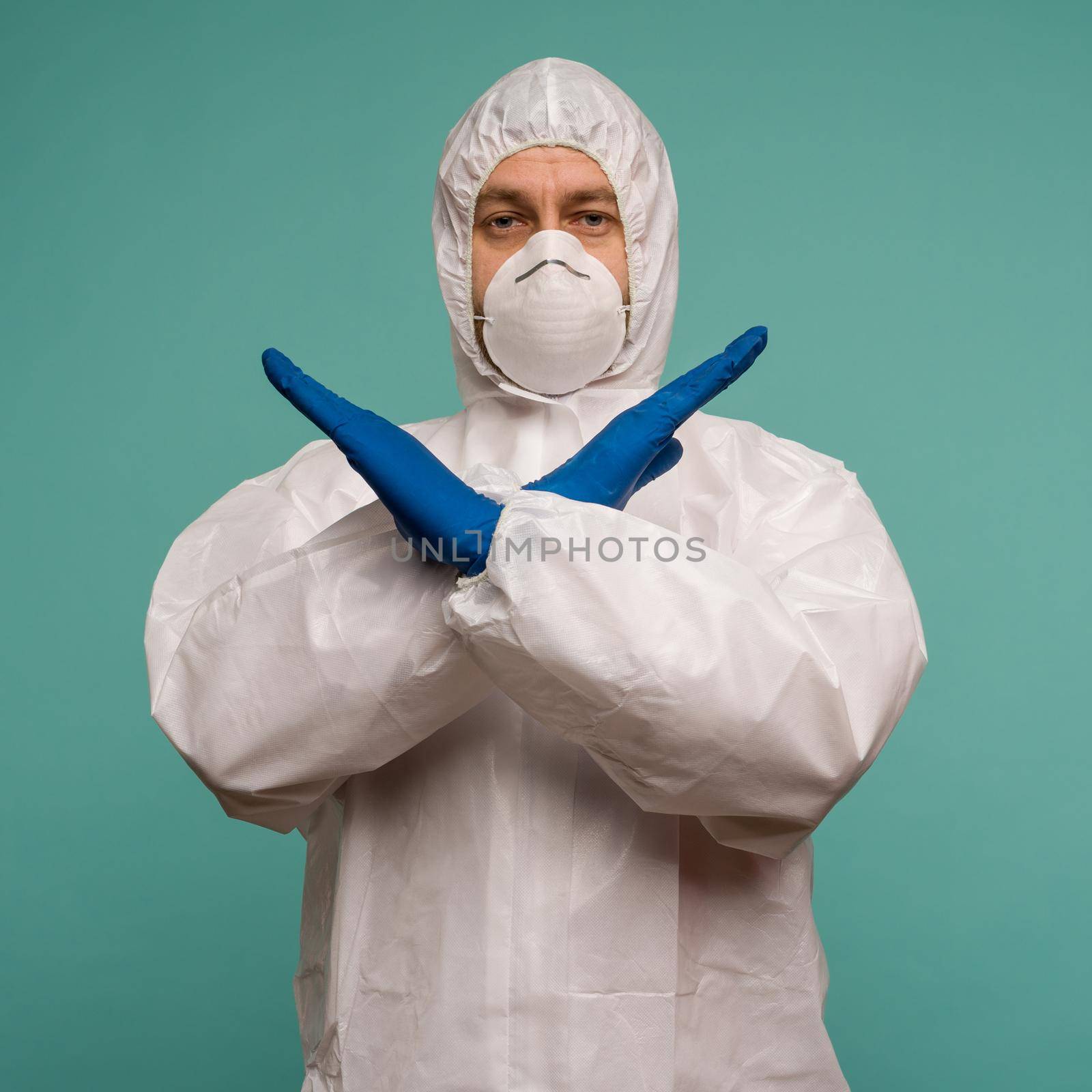 A male doctor in protective overalls and a mask shows stop sign. Coronovirus protection concept in China. by zartarn