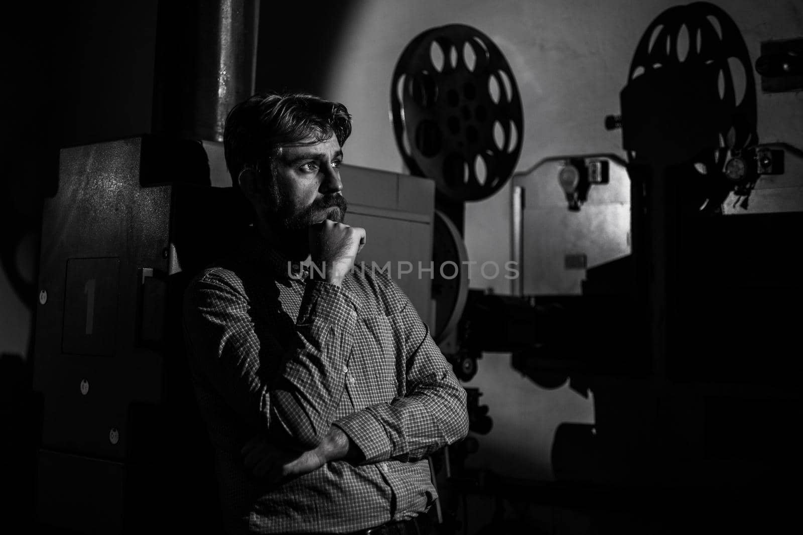 beautiful hipster man standing near a film projector in the room projectionist