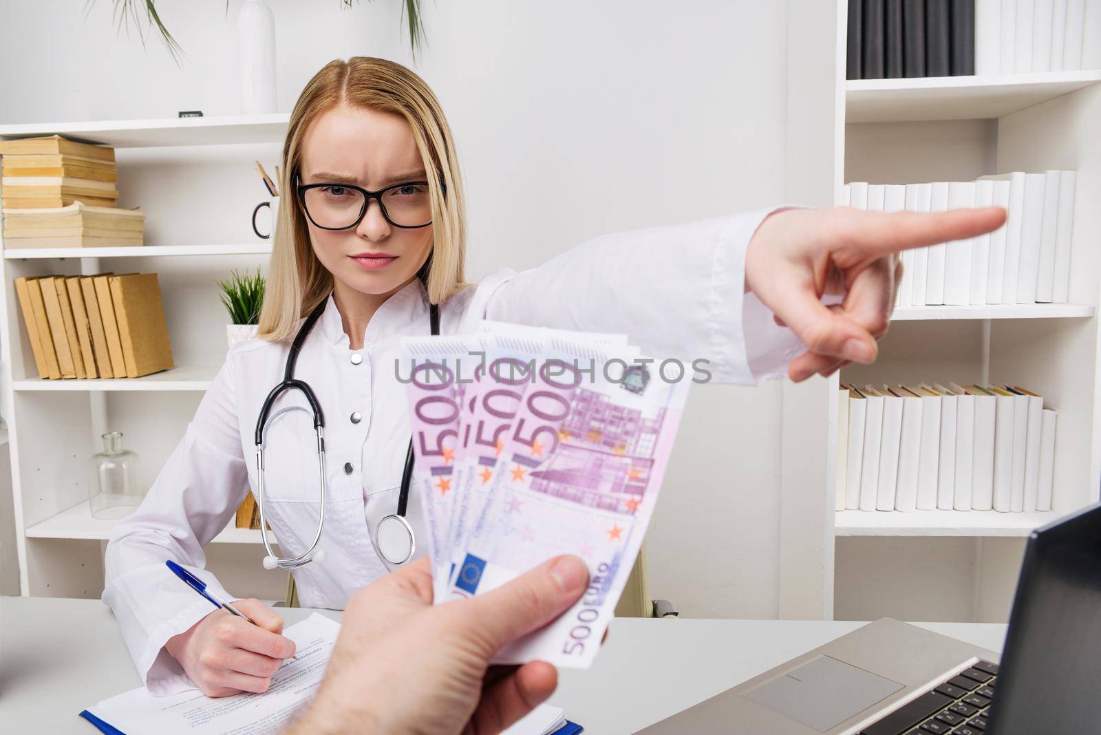 Woman doctor with stethoscope refusing bribes or kickbacks, currencies euro, patient giving money for medical services, concept of corruption - Image