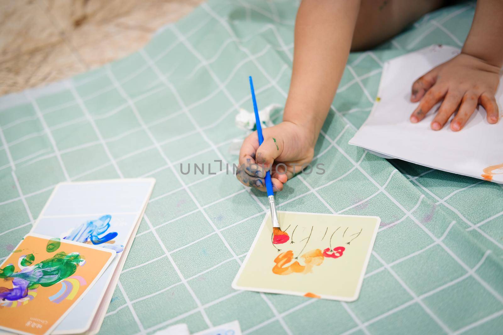 Focus on hands on paper. Children use paintbrushes to paint watercolors on paper to create their imagination and enhance their learning skills