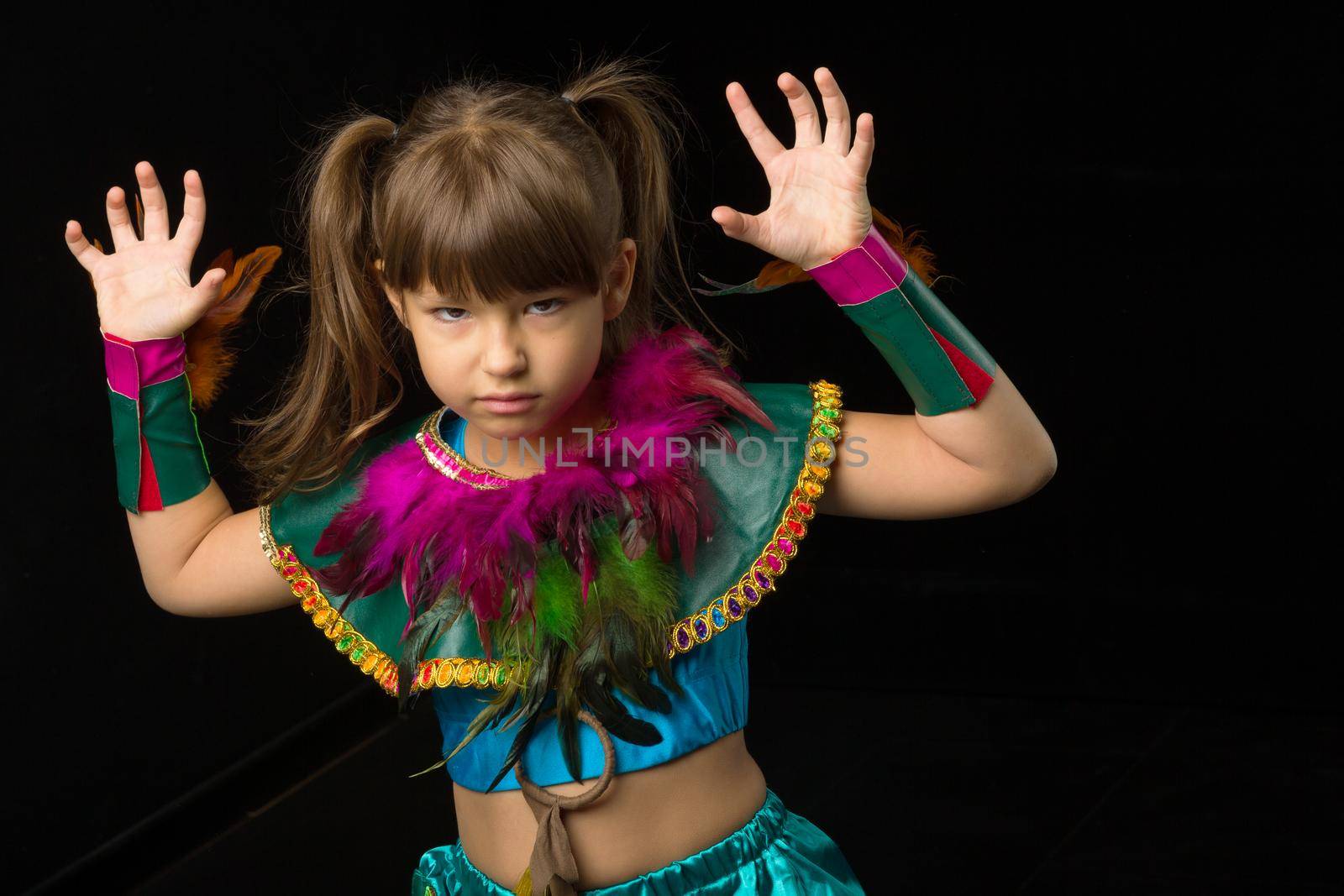 Girl growling like animal, making cat claws gesture. Portrait of beautiful preteen girl dressed ethnic costume standing on black background. Emotional child raising hands like paws posing in studio