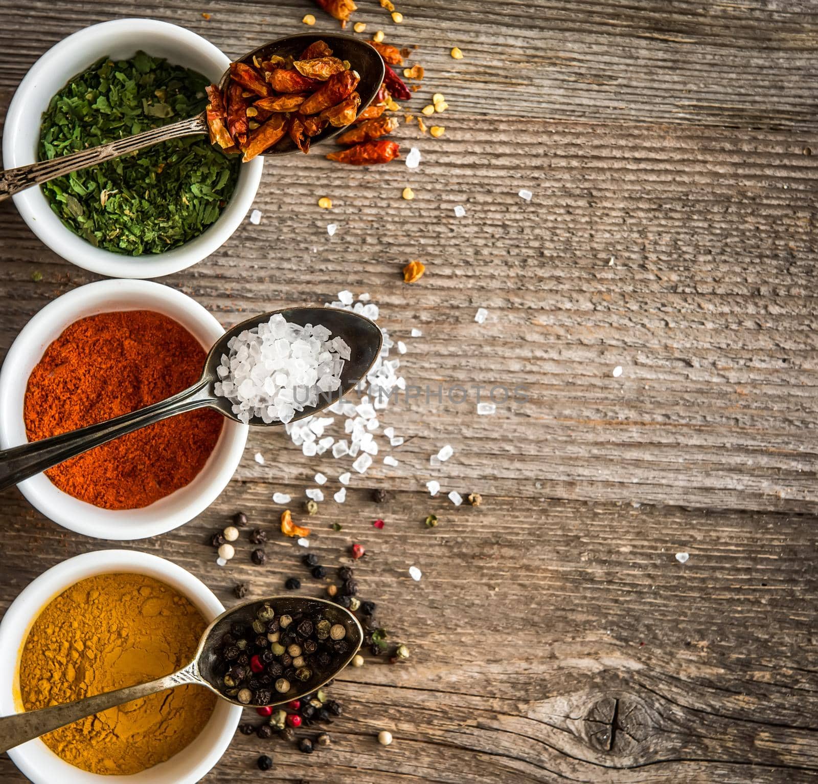different colorful spicec in bowls and spoons on wooden background