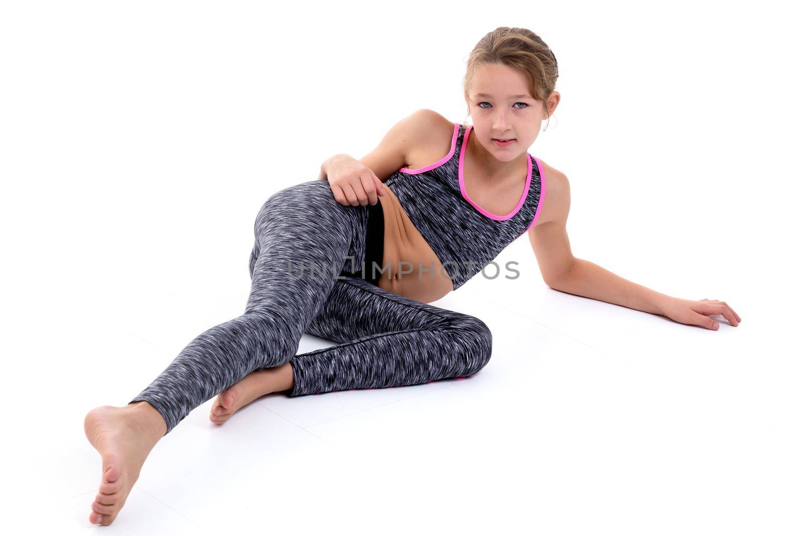 Beautiful little girl lies on the floor on a white background. The concept of style and fashion, children's emotions. Isolated.