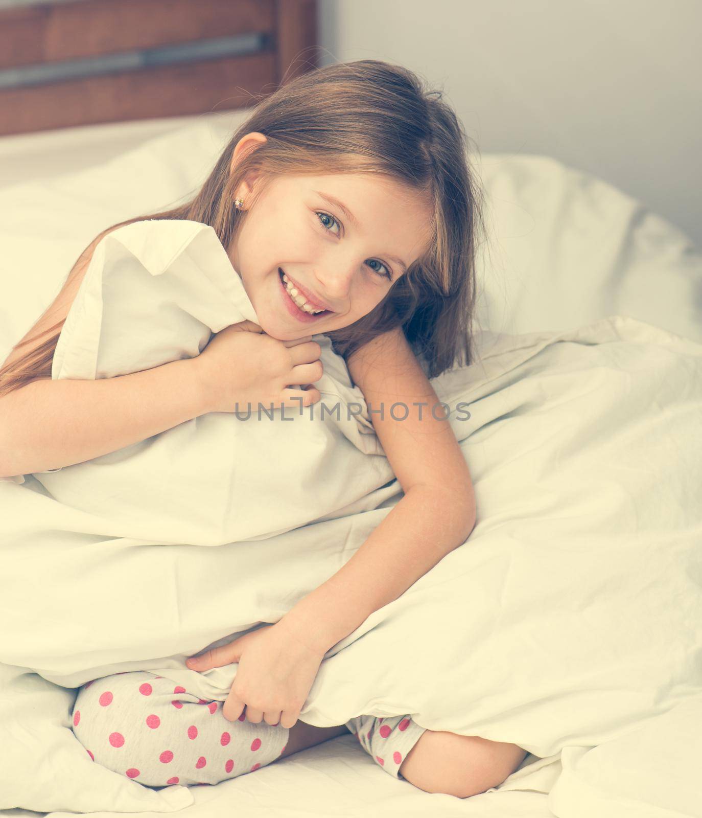 cute little girl in a bad holding a blanket