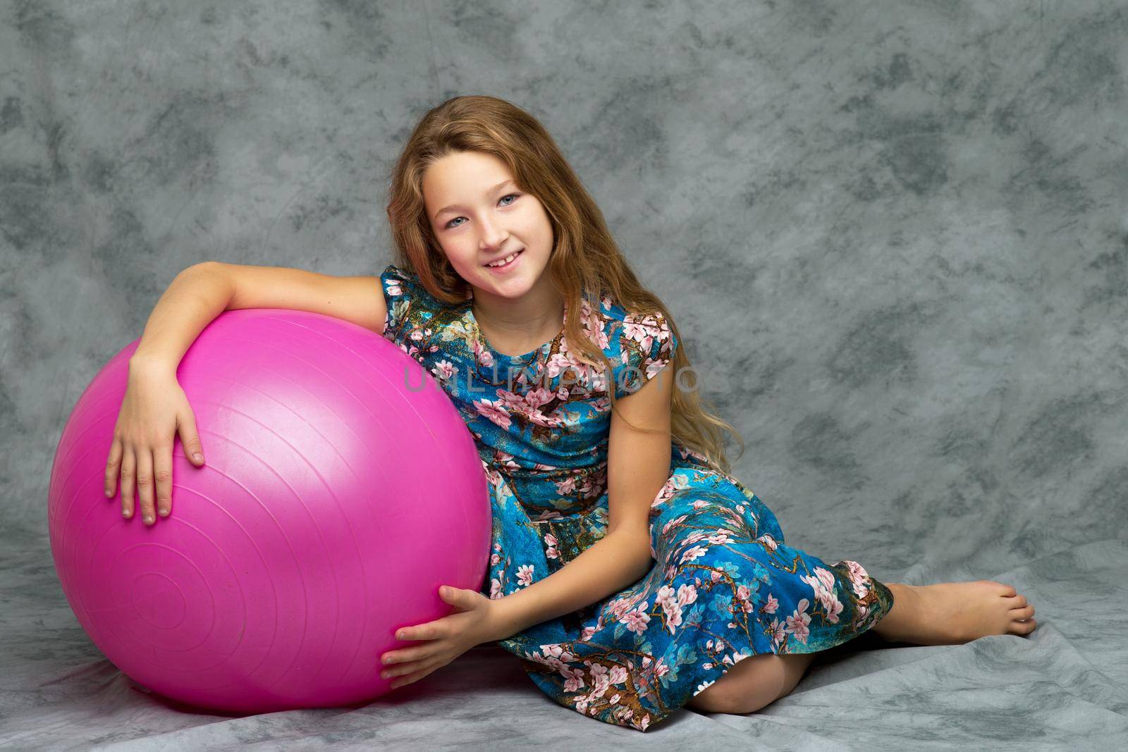 A good girl is playing with a big inflatable ball. The concept of a happy childhood, recreation in nature, exercise. Isolated on white background.