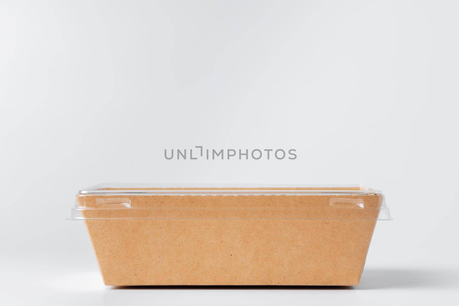 Craft paper disposable box with plastic cover on grey background, copy space, close up