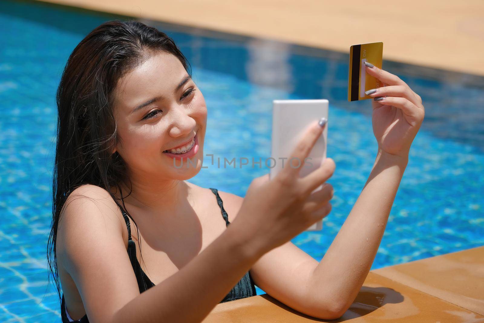 online payment, A teenage girl who swims is using her credit card with her phone to make purchases. online via internet.. by Manastrong