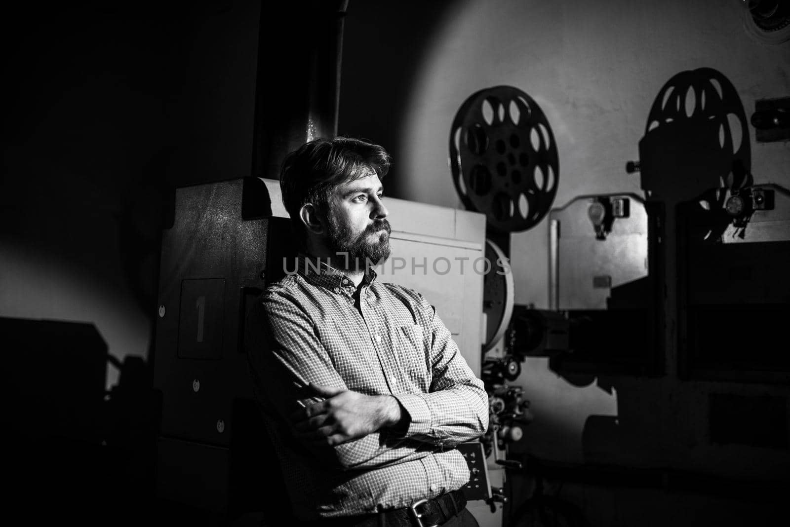 man standing near a film projector in the room projectionist by zartarn