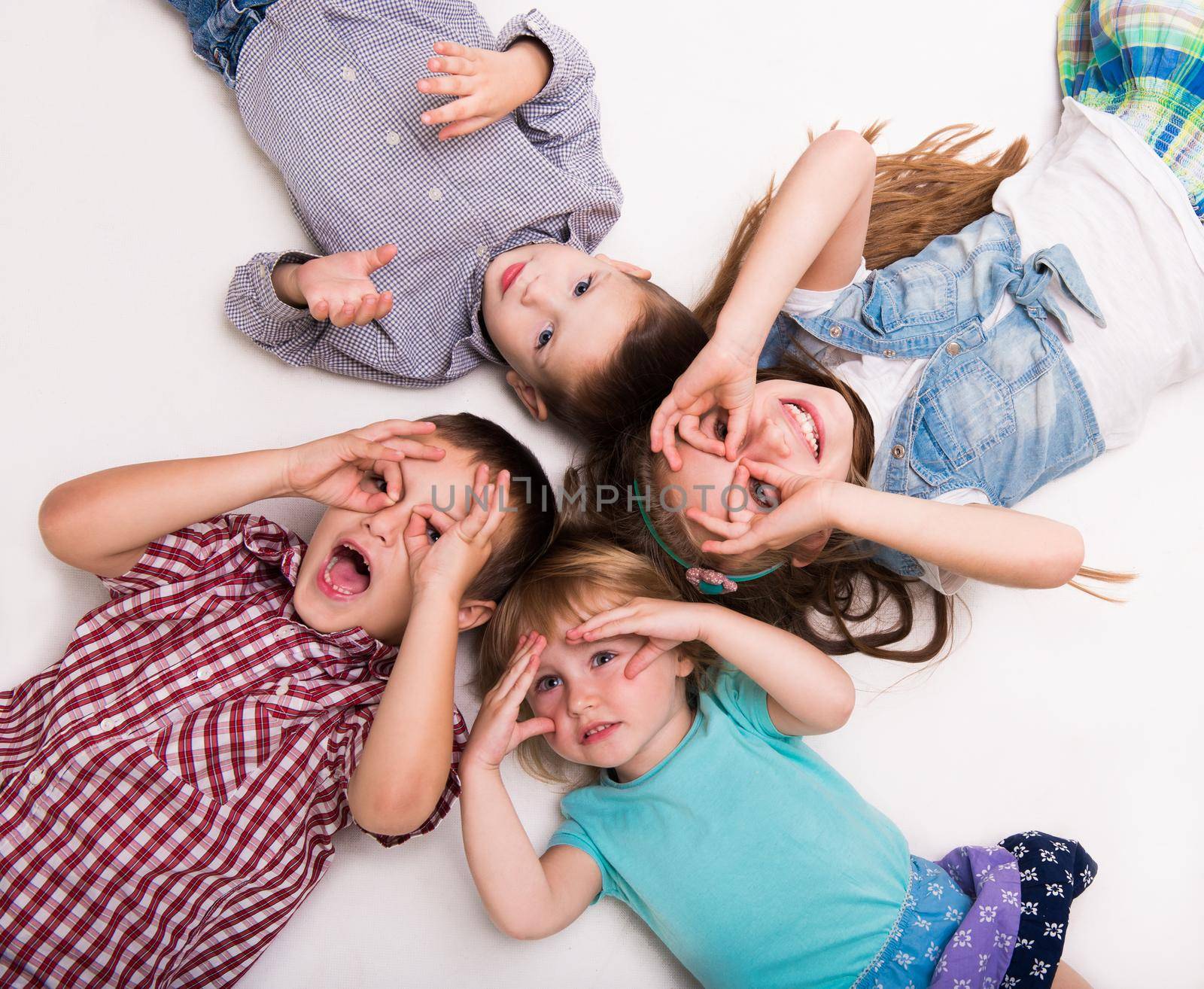 children lying on the floor with hands imitating glasses isolated on white background