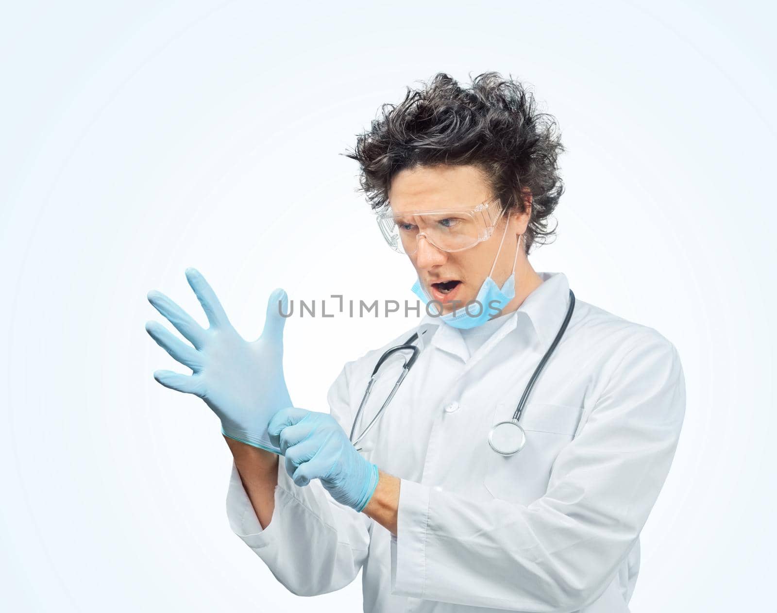 Funny man doctor is putting on gloves in blue background