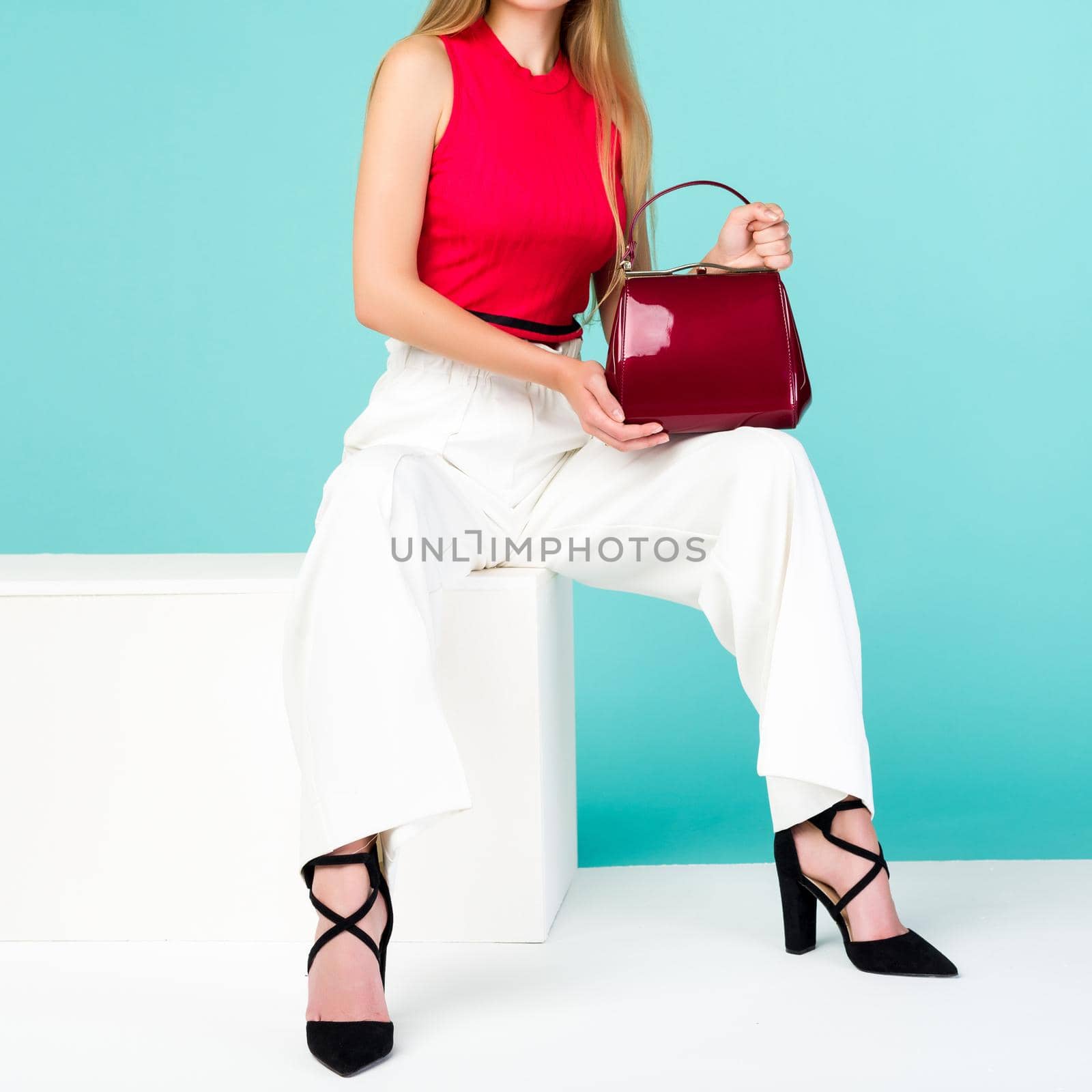 Beautiful woman sitting on the bench with red handbag purse and high heel shoes. - image