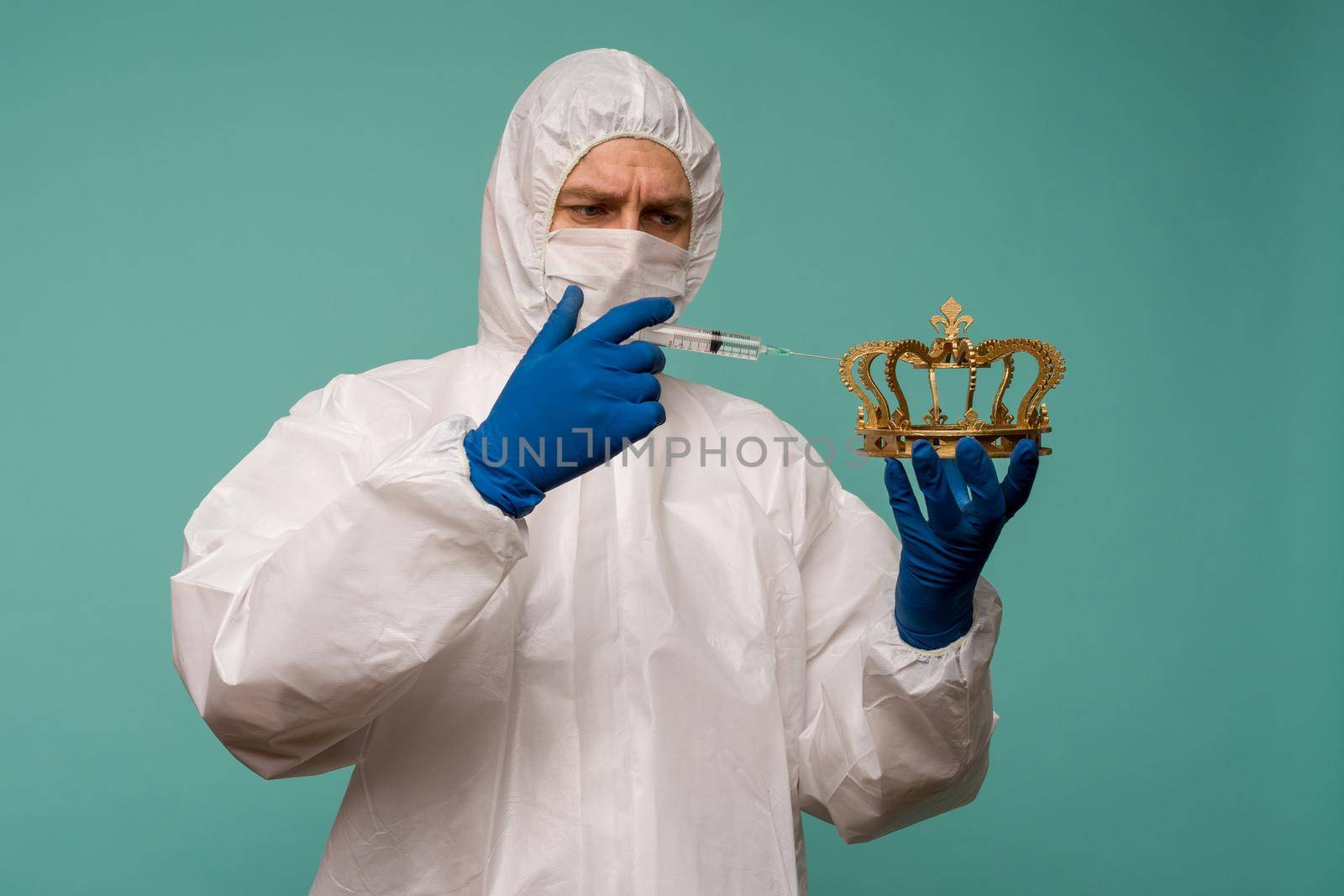 A male doctor in protective overalls and a mask makes an injection in the crown. Coronovirus protection concept in China. - image