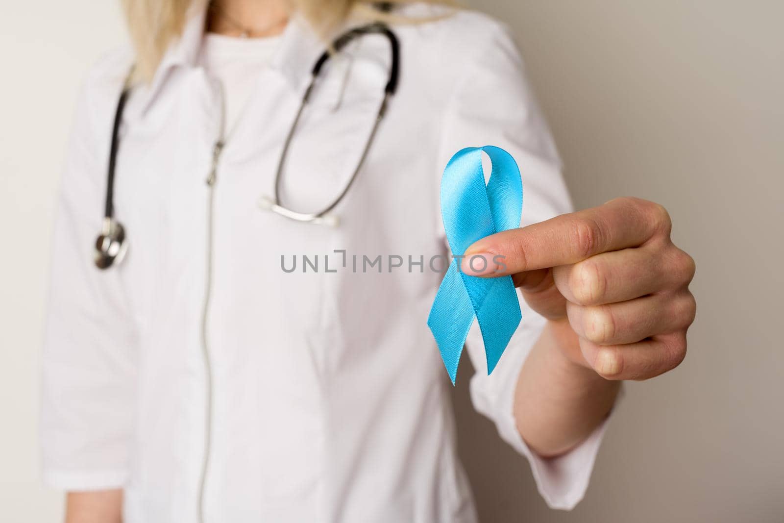 Female doctor holding a blue ribbon in her hands - image