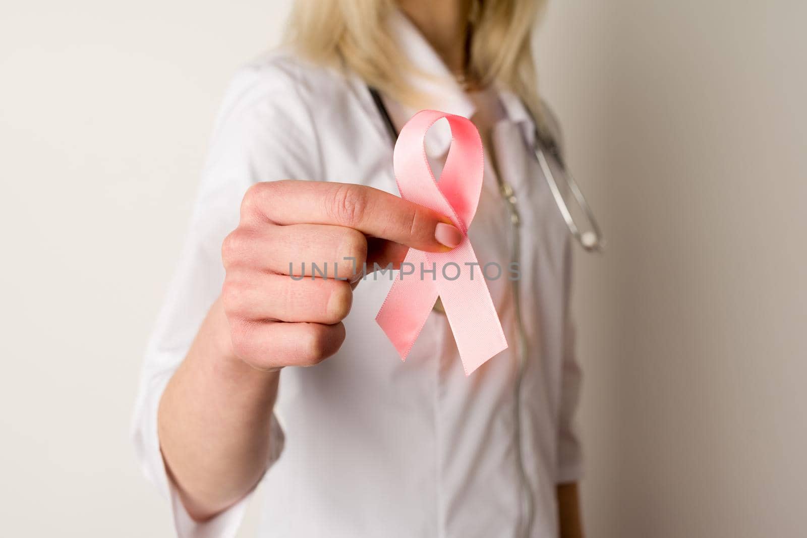 Woman doctor holding a pink ribbon in her hands - image