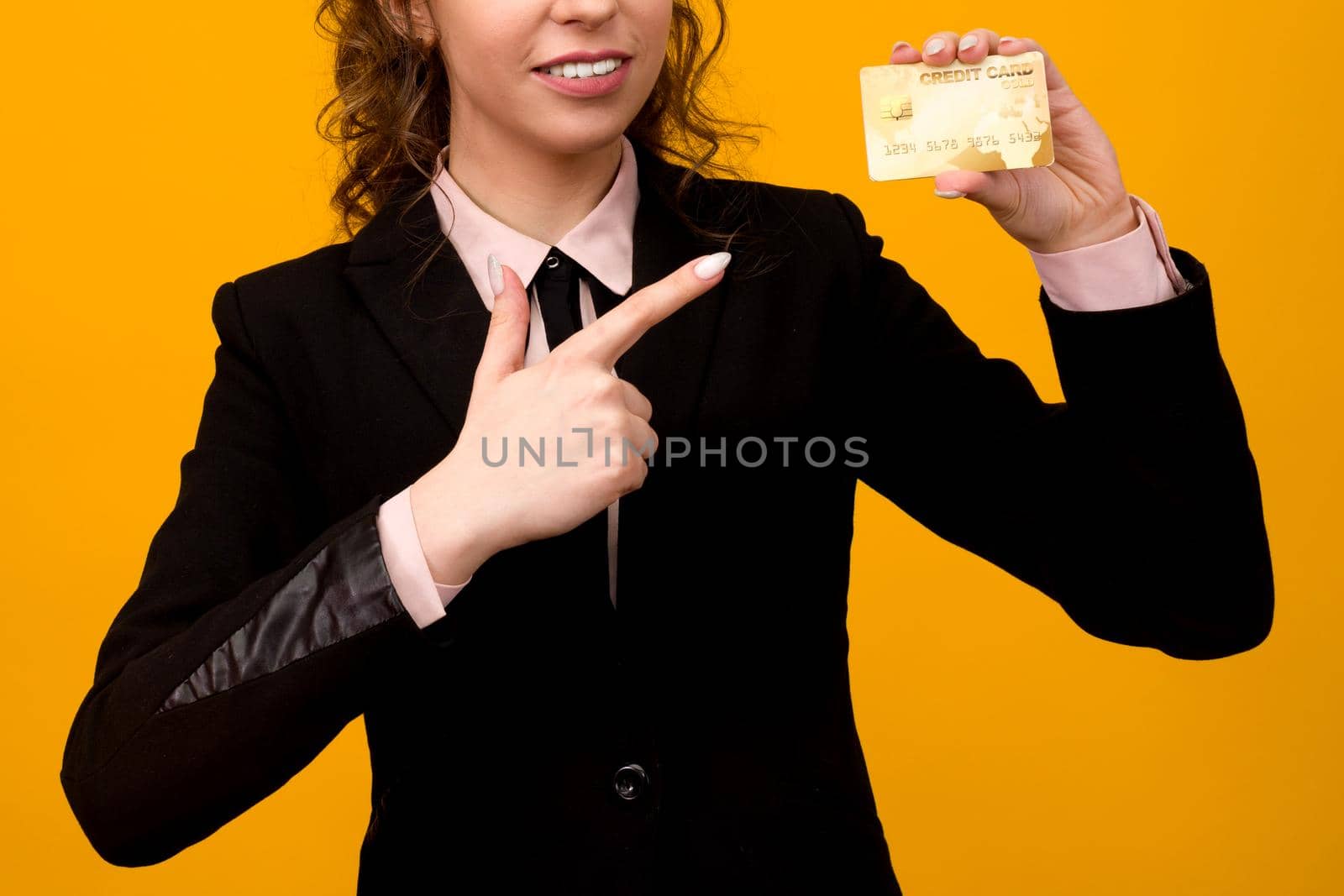 Portrait of a beautiful young business woman standing isolated over yellow background, holding credit card by zartarn