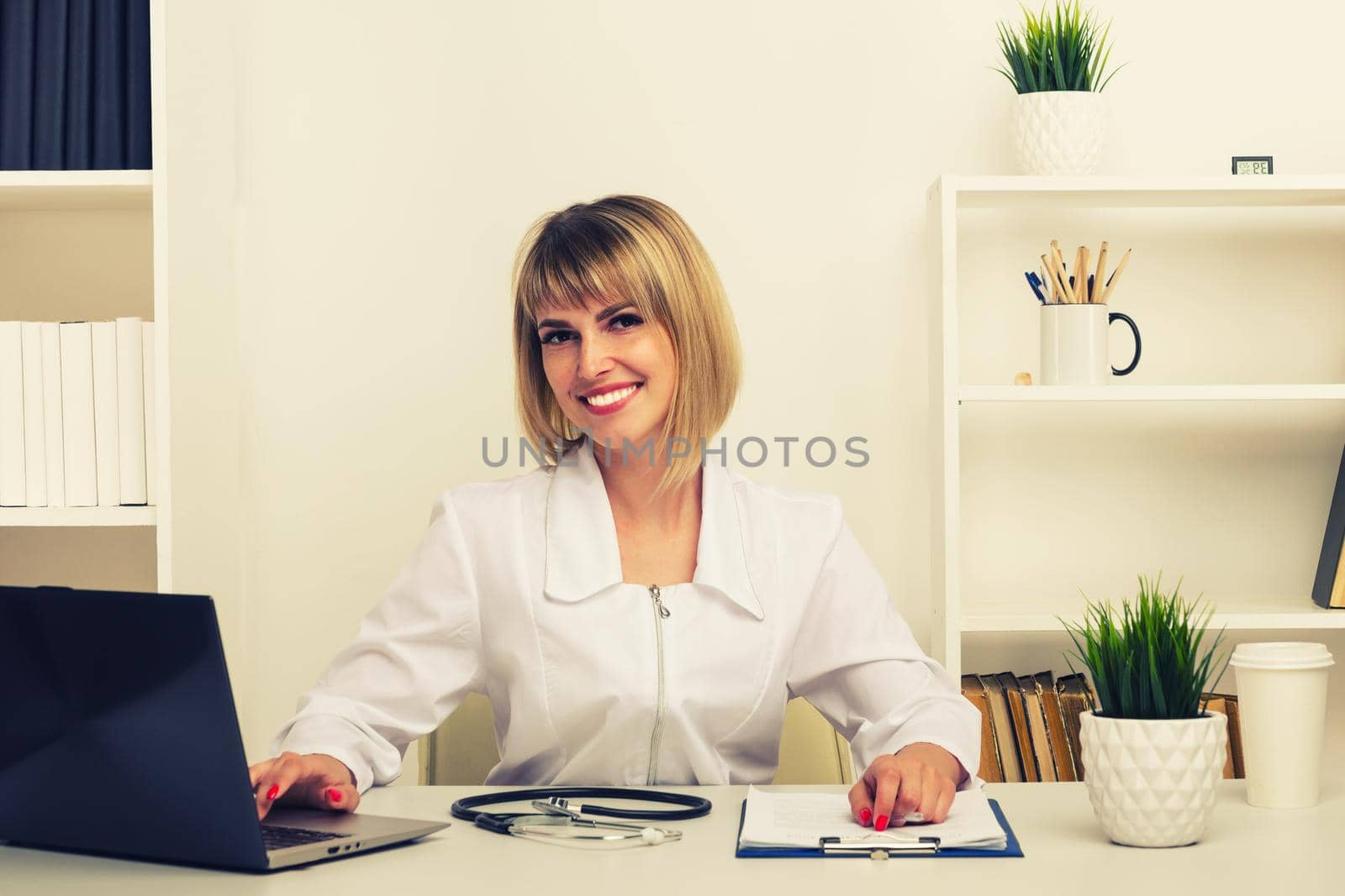 Friendly female doctor works at her desk in the office - image toned