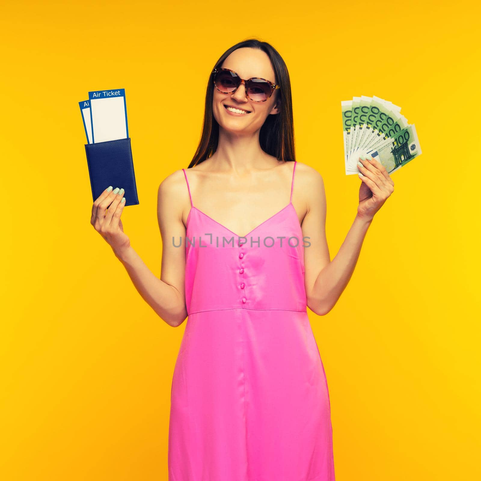 Slender girl in a pink dress and sunglasses holding passport with air ticket and hundred euro bills by zartarn