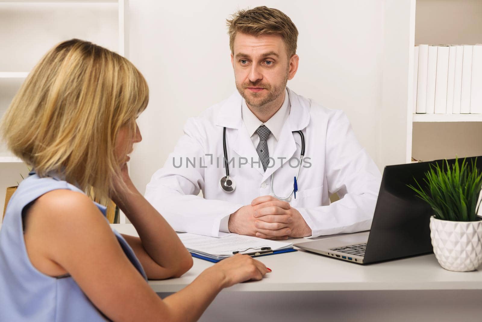 Young woman on a consultation with a male surgeon or therapist in his office. Selective focus on the doctor.