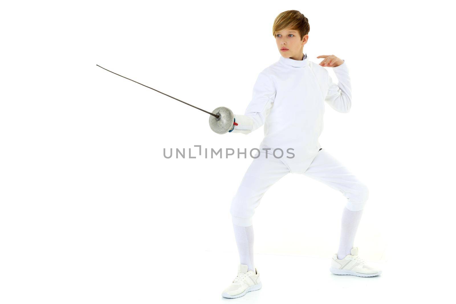 Fencer boy practicing effective technique. Portrait of handsome teenage boy fencing player wearing white uniform fighting with foil against white background.