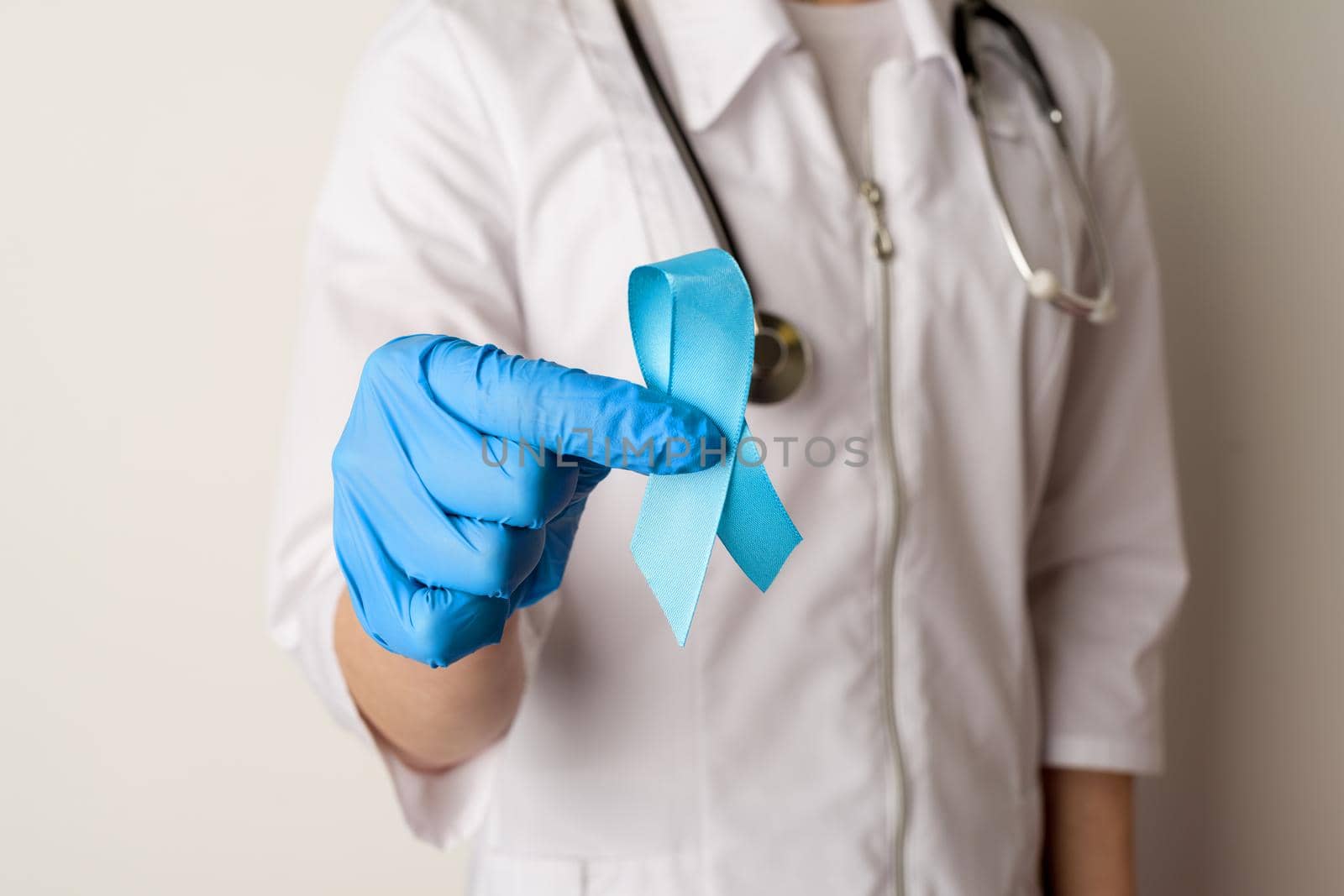 Female doctor holding a blue ribbon in her hands - image