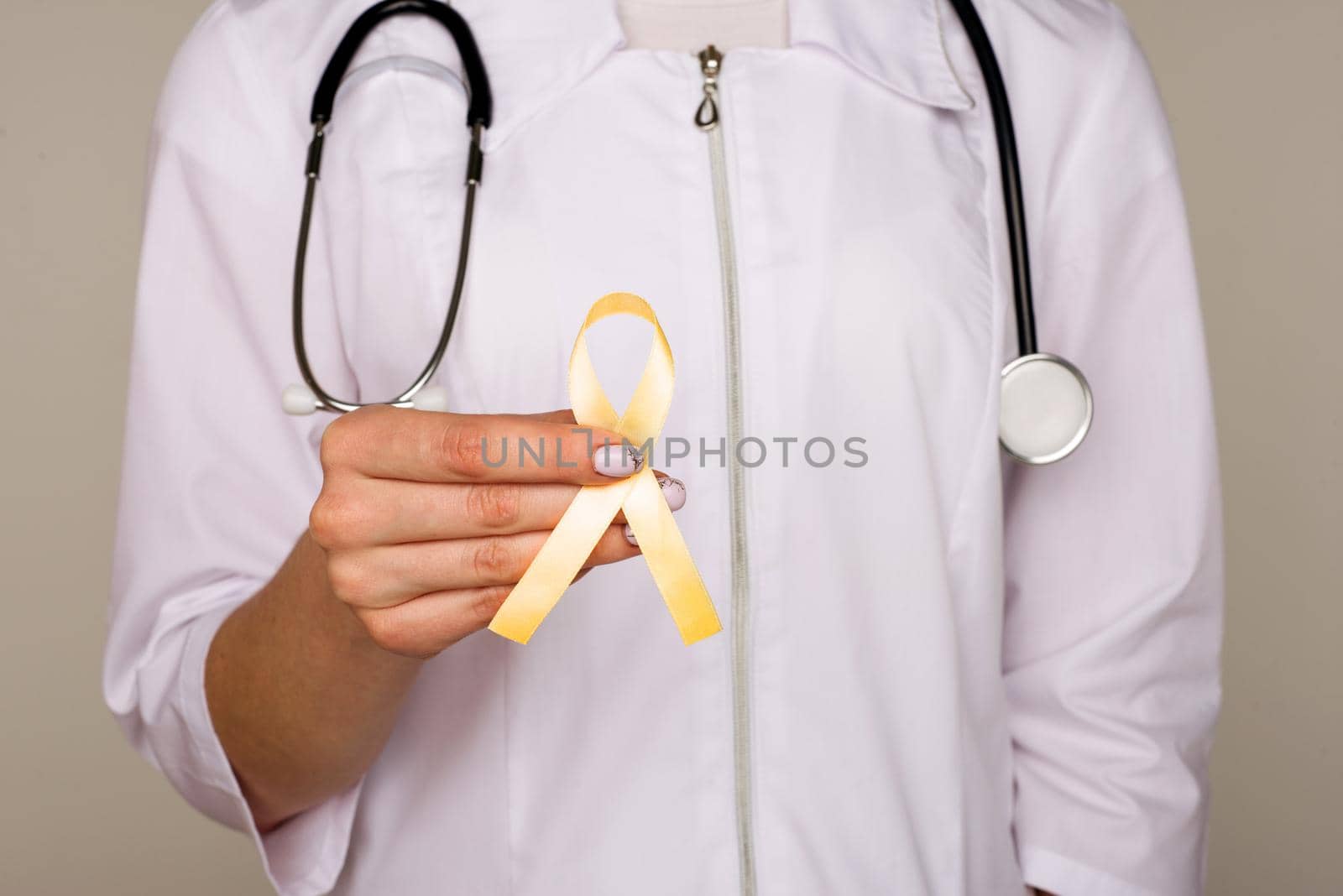 Yellow ribbon symbolic color for Sarcoma Bone cancer, Bladder health, Liver disease, Spina Bifida Awareness Month and suicide prevention in doctor's hand - Image