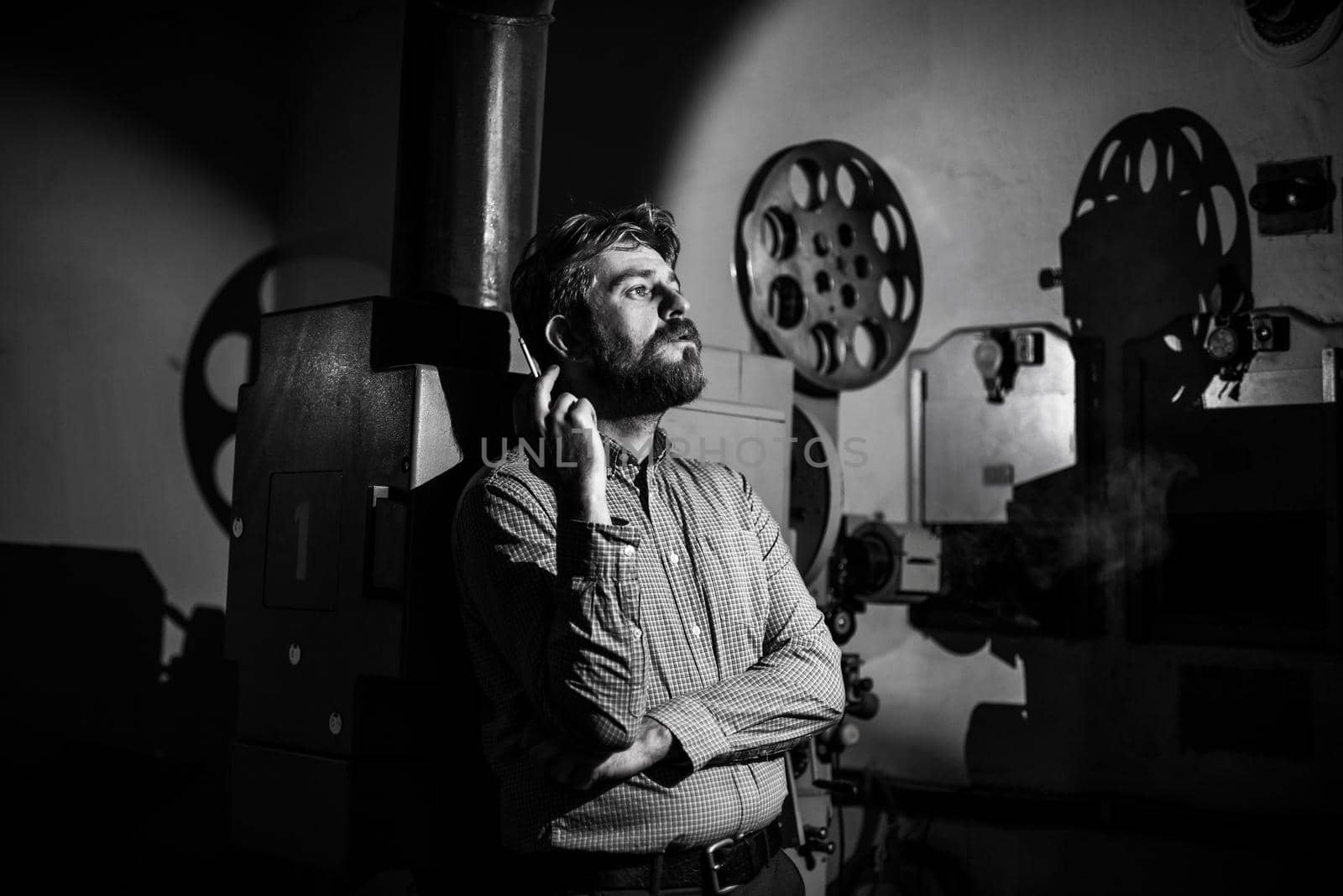 beautiful hipster man standing near a film projector in the room projectionist