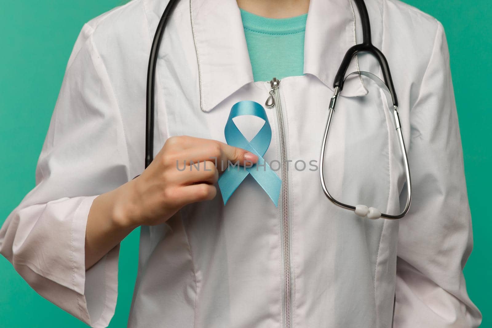 Blue ribbon for prostate cancer awareness campaign and men's health care concept with symbolic bow in doctor's hand - image