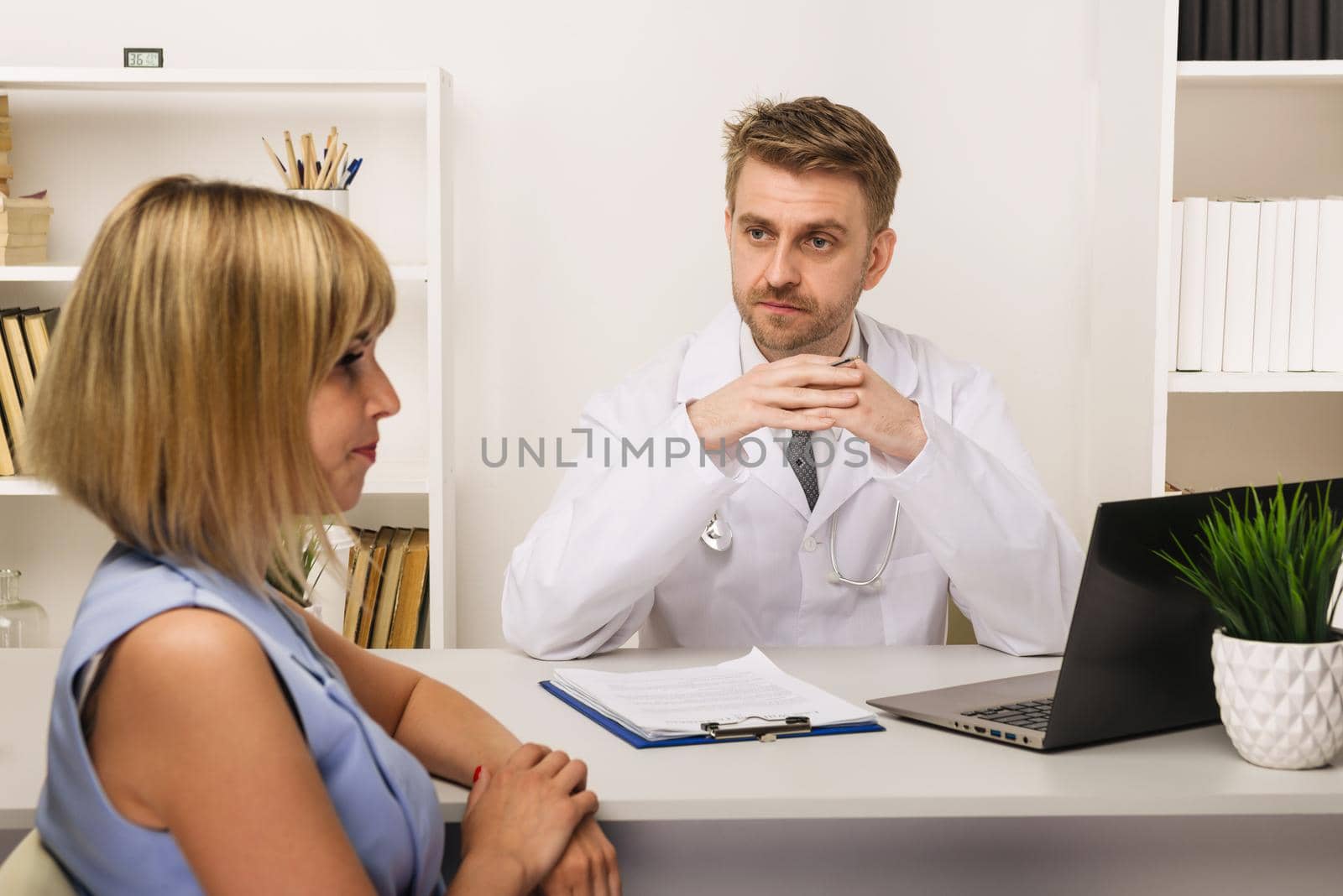 Young woman on a consultation with a male surgeon or therapist in his office. Selective focus on the doctor.